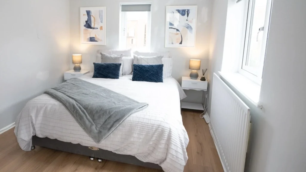Spacious double bedroom with a comfortable bed and scenic window views in serviced apartments Stratford upon Avon