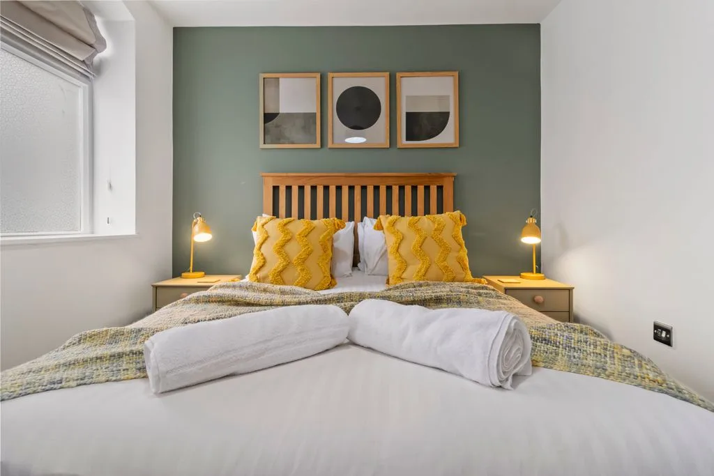 Stay in a luxury room in Worcester with a king bed adorned with yellow pillows, offering both comfort and elegance for a restful stay.