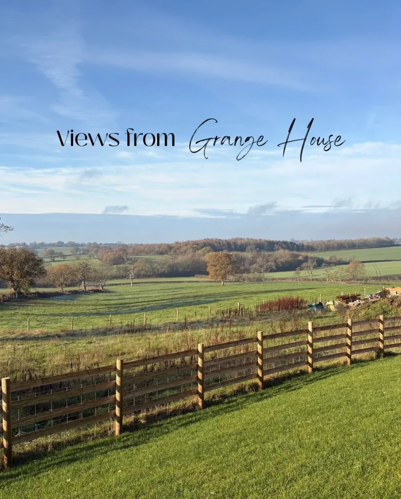 A wide green hillside and woodland landscape visible from a cozy UK accommodation window.